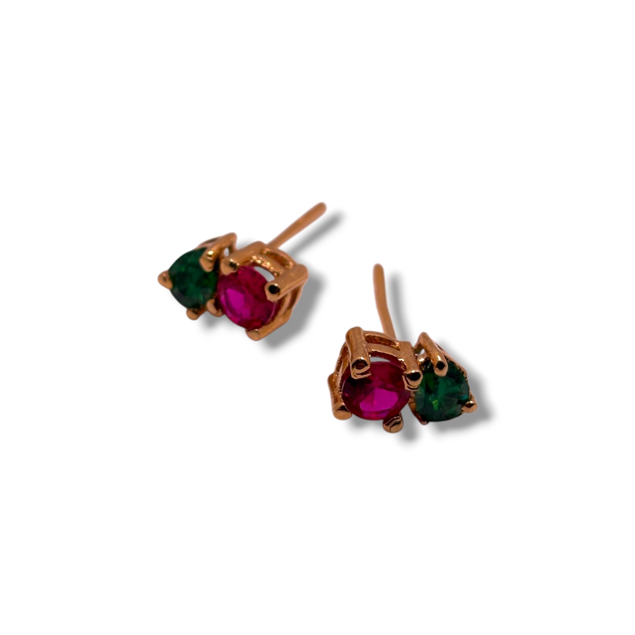 Pair of gold stud earrings with red and green gemstones on a white background