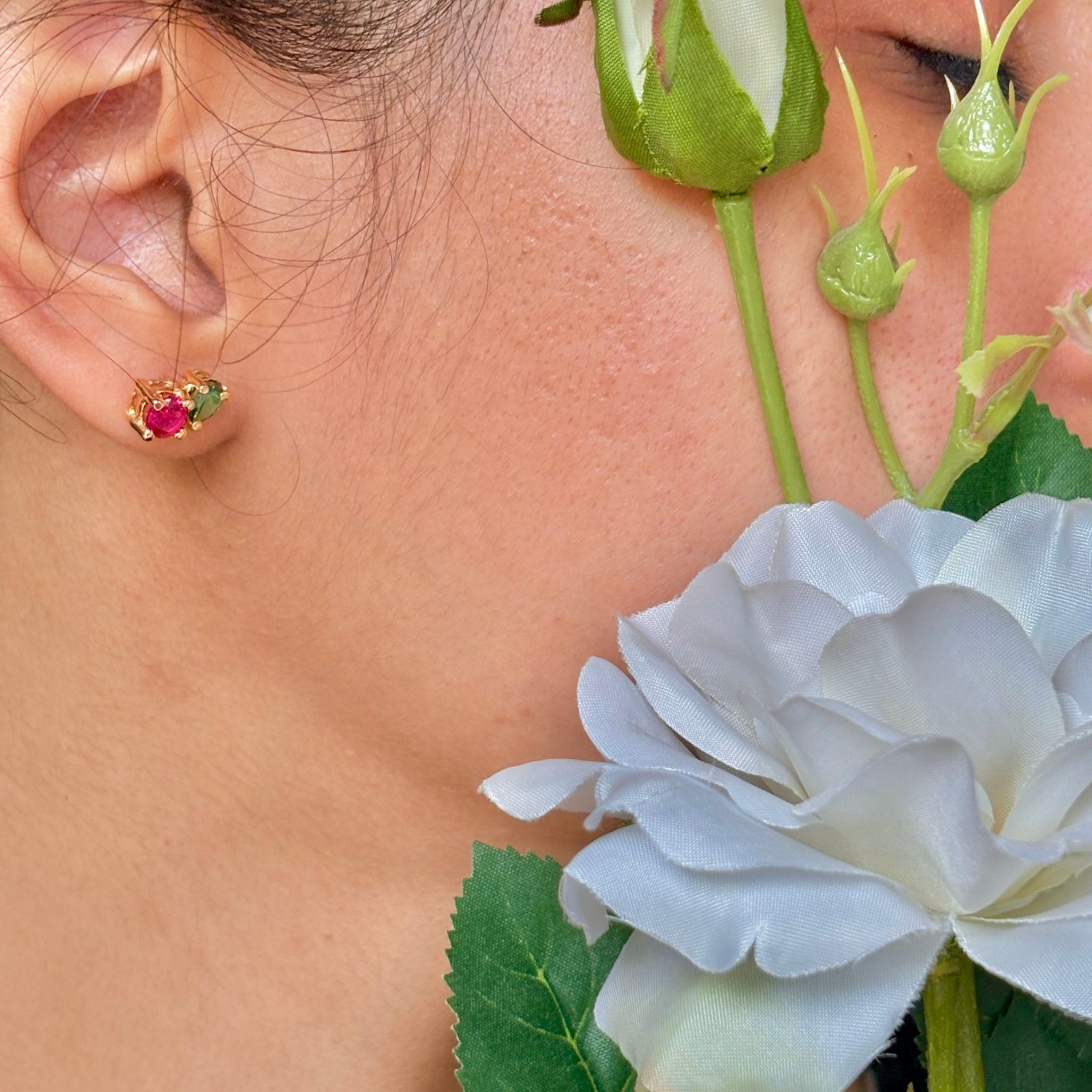 Close-up of a person wearing a floral earring with a white flower in the foreground.